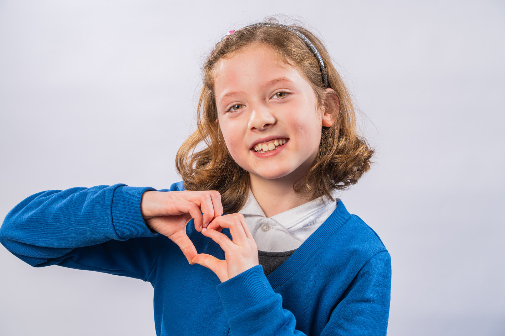 Individual school portrait - girl making heart gesture